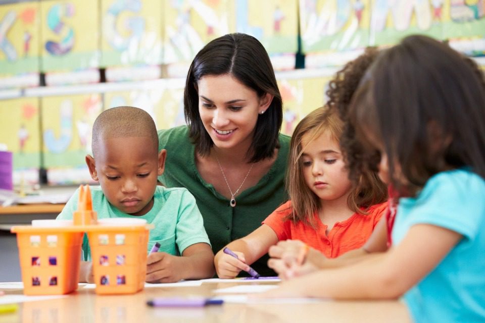 Elementary art class drawing with teacher at table